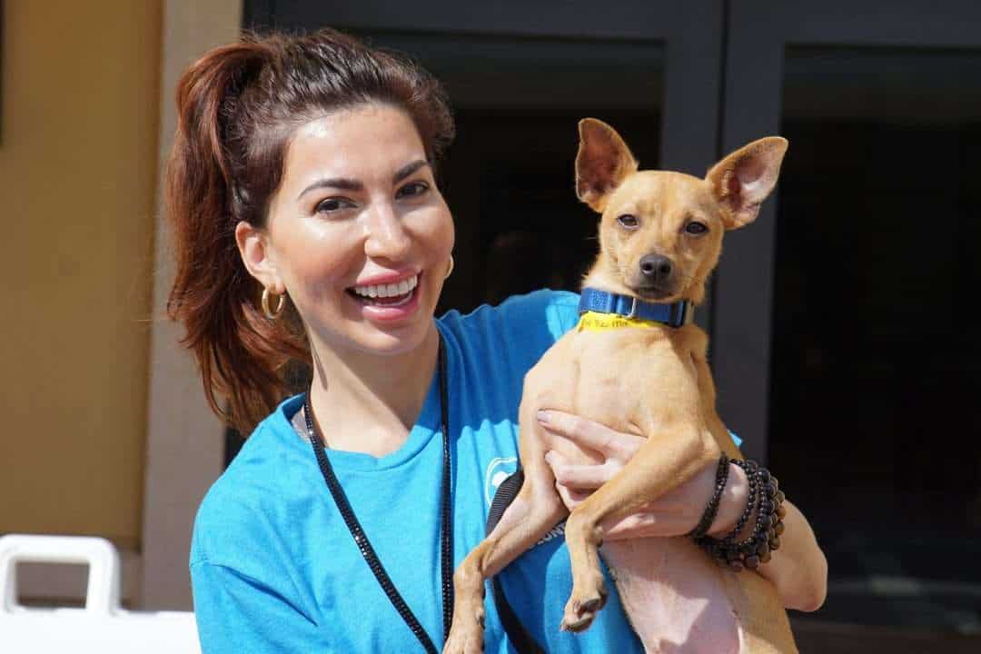 Mujer durante el voluntariado sonriendo sosteniendo un perro pequeño