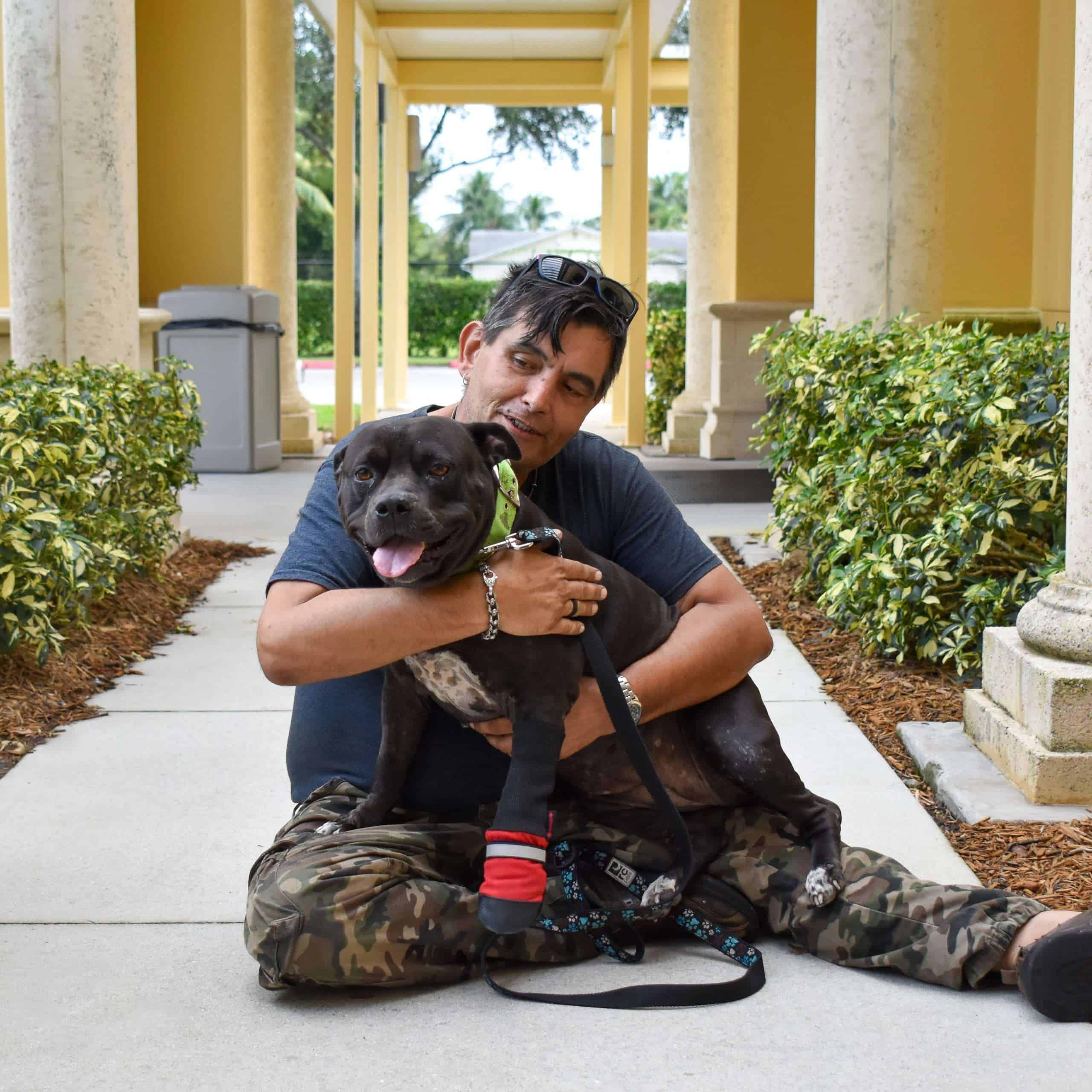 Man hugging a happy dog outside Peggy Adams shelter.