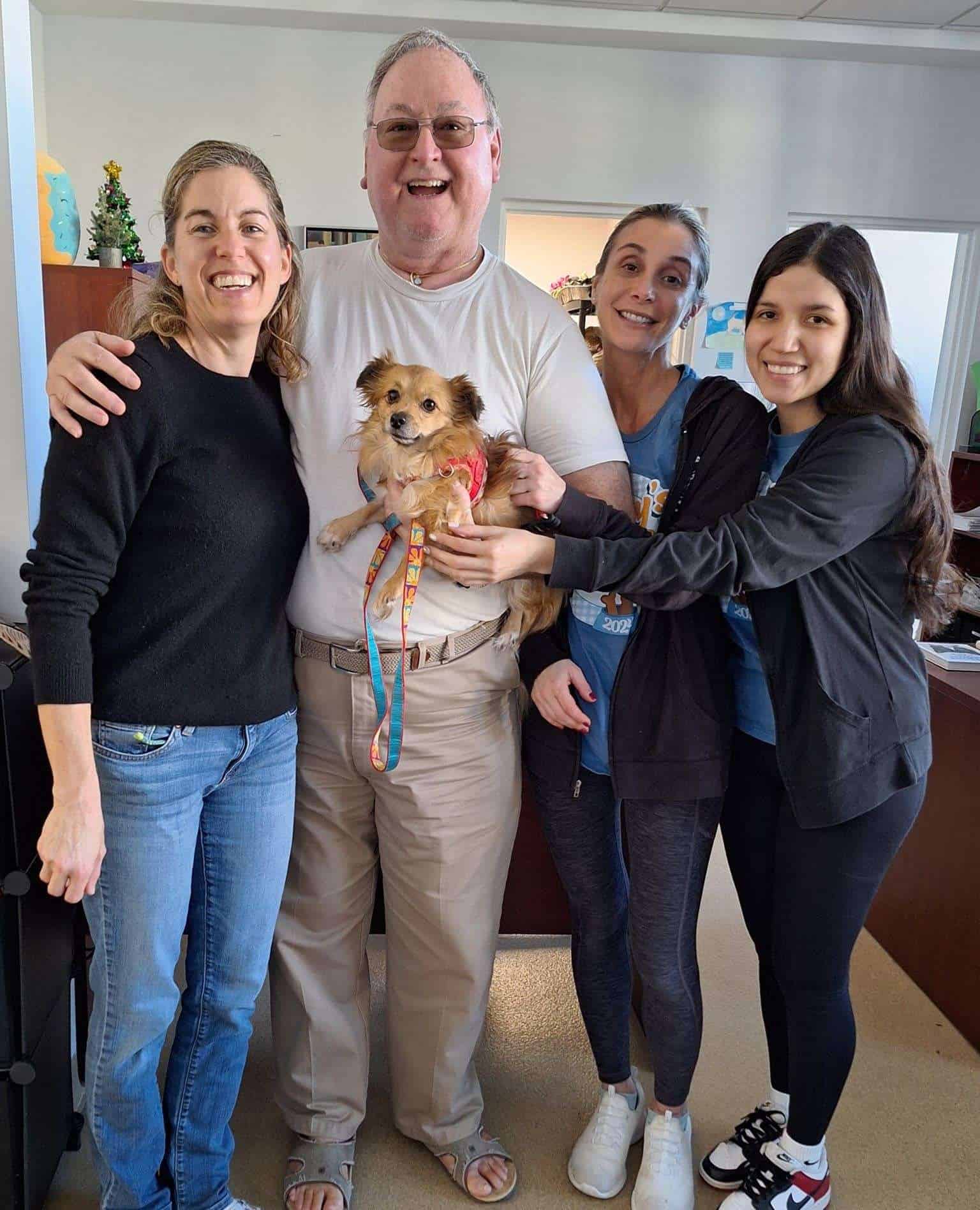 Grupo feliz con un perro pequeño en Peggy Adams Animal Rescue.