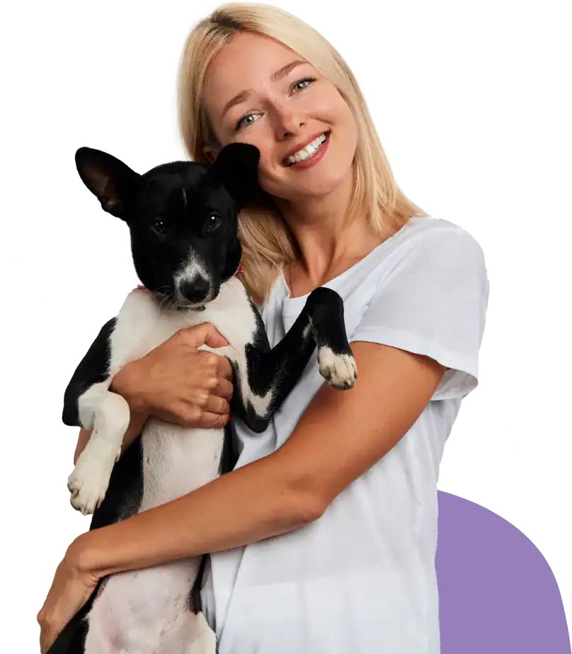 Woman holding a black and white dog, smiling happily.