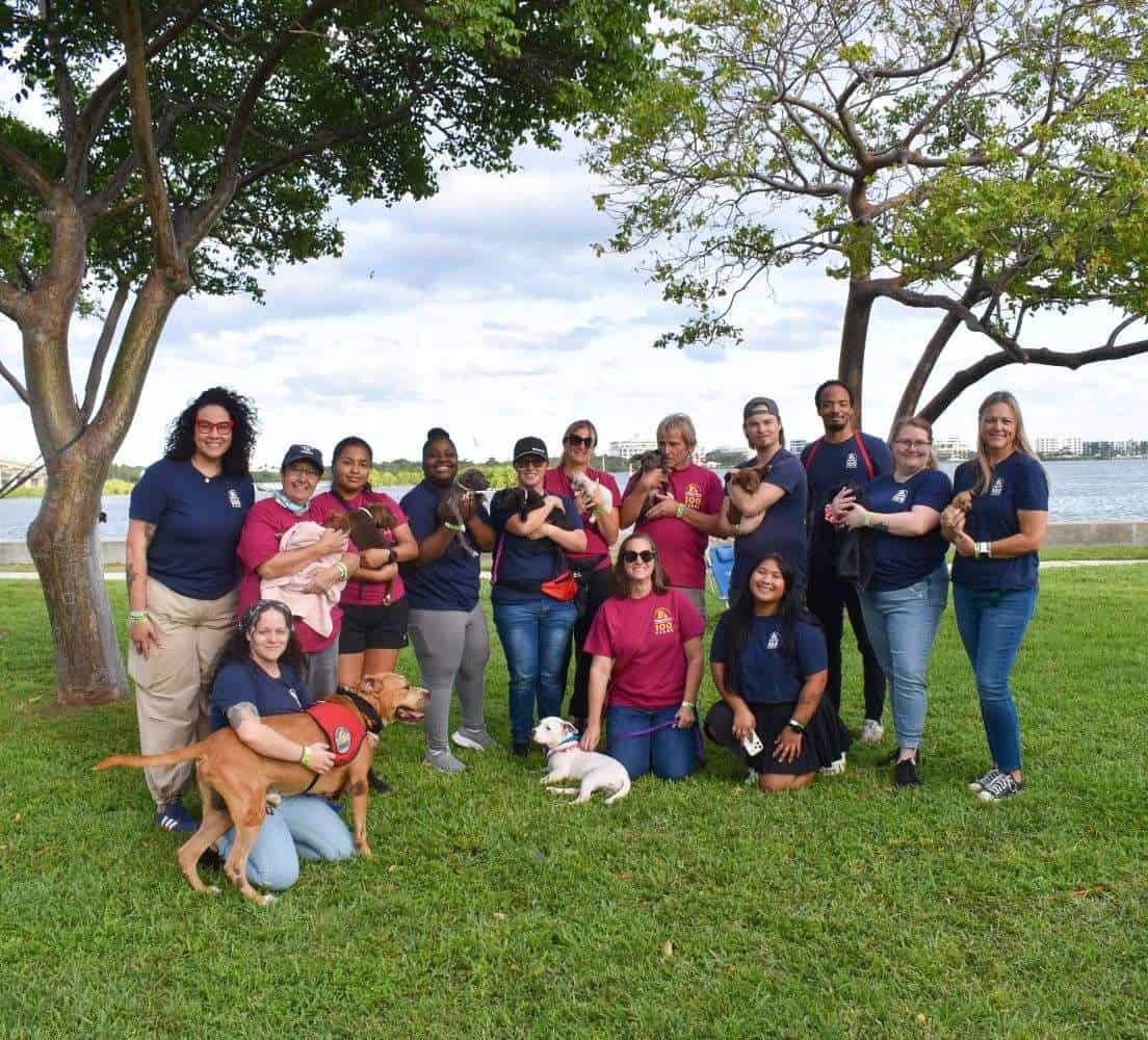 Group of volunteers with adopted pets at Peggy Adams outdoor event.