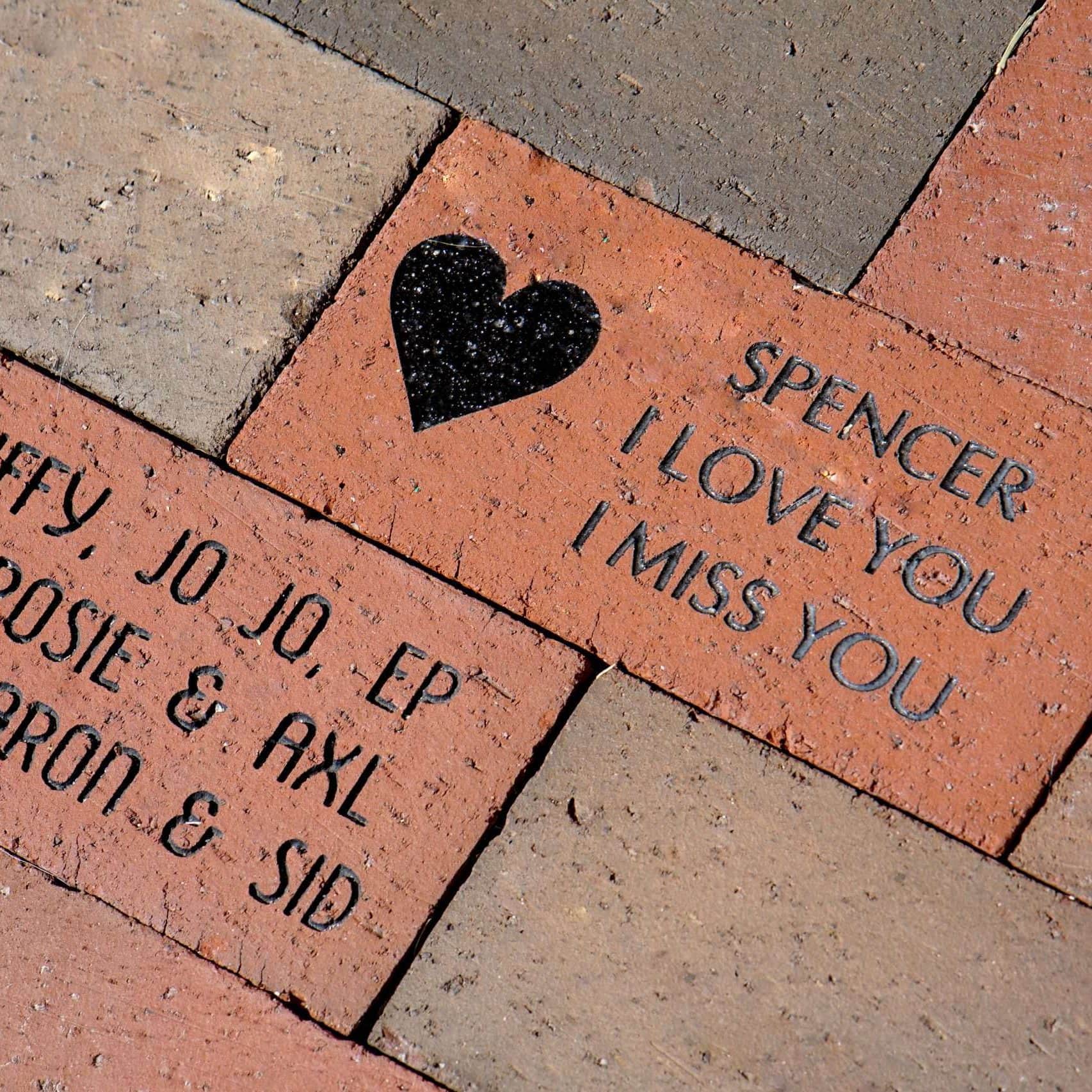 Ladrillo grabado con mensaje de amor para Spencer, que dice "Te quiero" y "Te extraño".