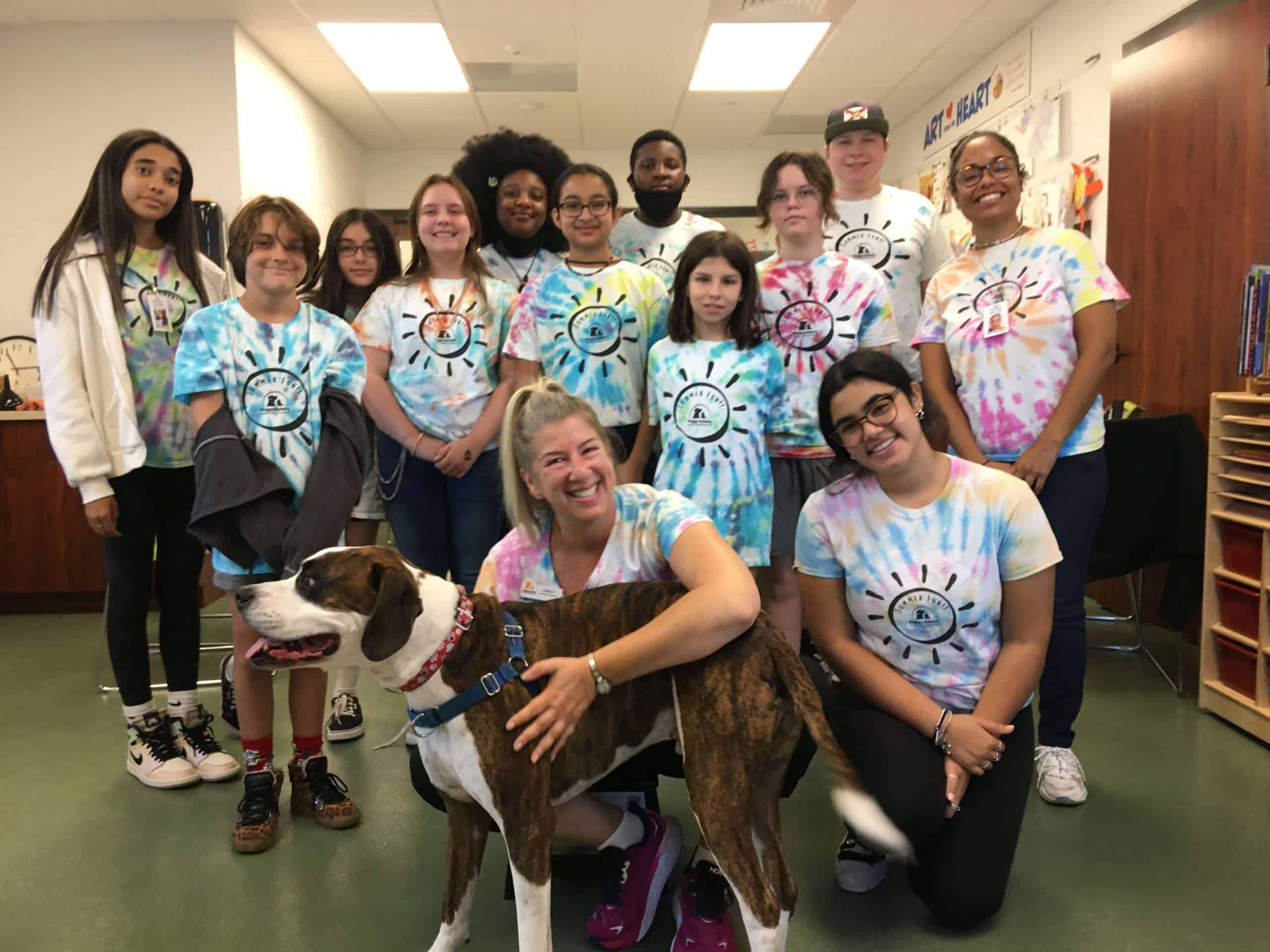Community group of diverse children and adults wearing colorful tie-dye shirts at Peggy Adams Animal.