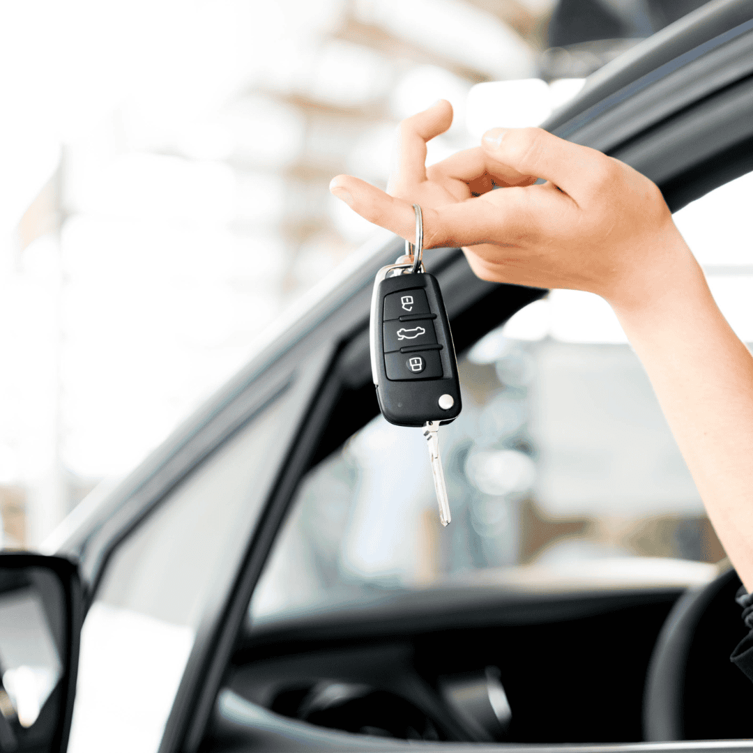Persona sosteniendo la llave de un auto fuera del vehículo, toma de cerca.