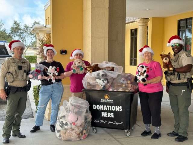 Volunteers and officers with stuffed animals donating to Peggy Adams Animal Rescue.