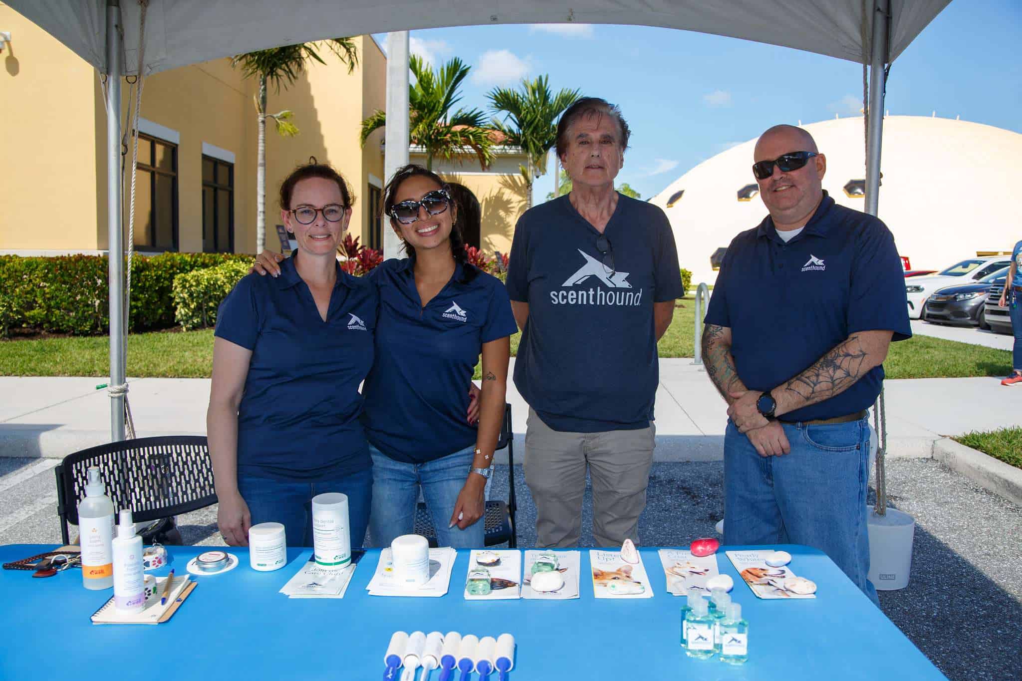 Peggy Adams team at outdoor dog adoption event with pet care products.