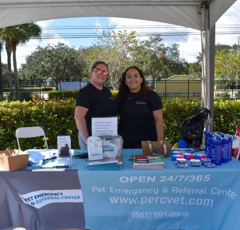Two women at a pet emergency center outreach booth outdoors.