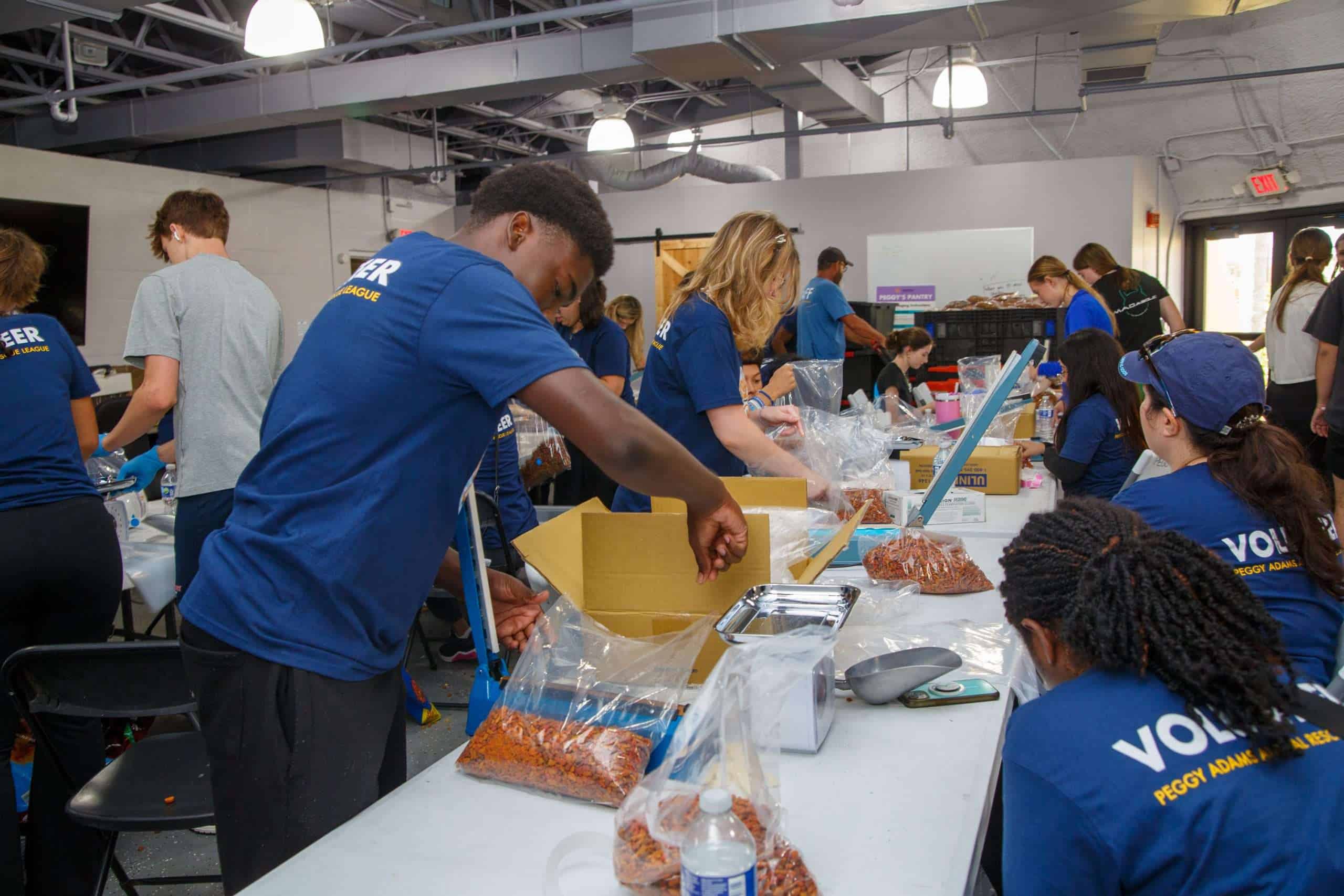 Voluntarios empacando comida para mascotas para animales necesitados en Peggy Adams.