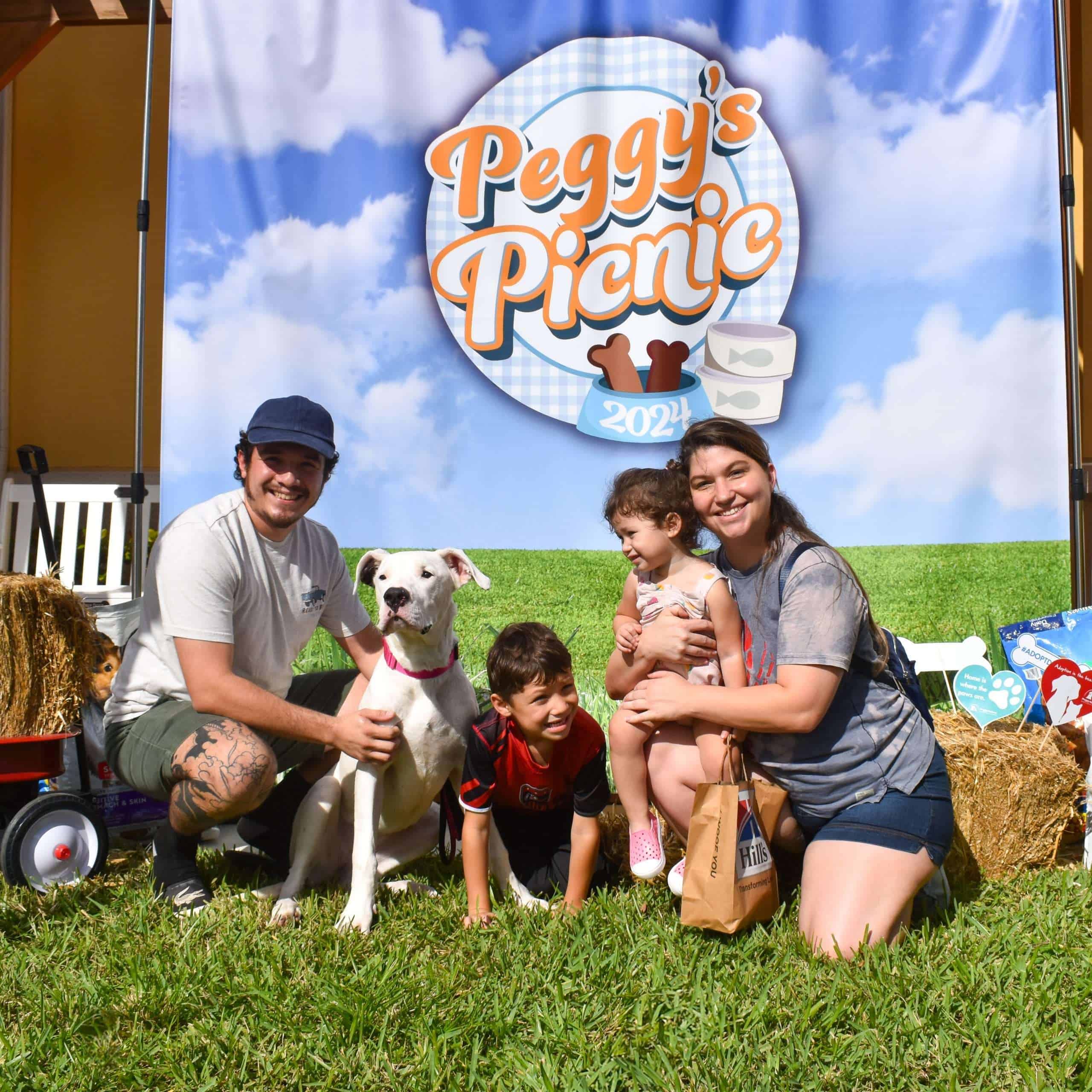 Familia disfrutando un picnic de Peggy con mascotas en un evento al aire libre.