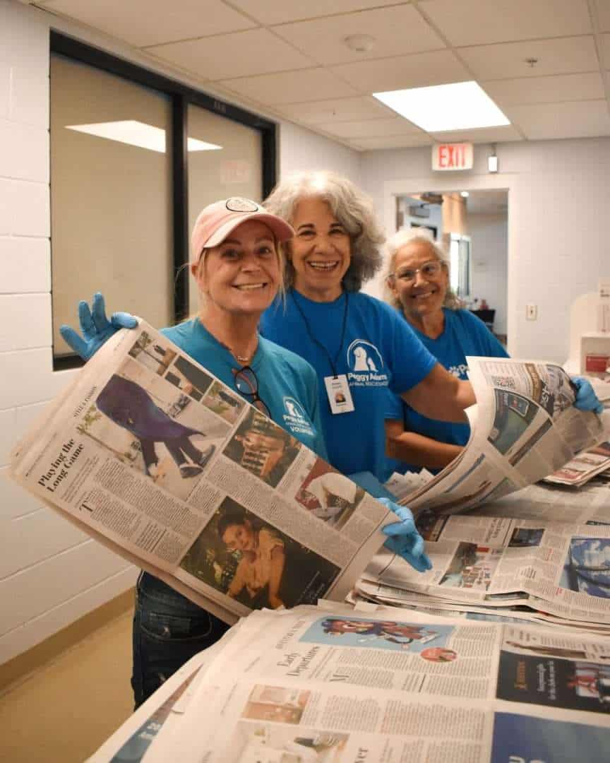 Community volunteers sorting newspapers for recycling or distribution.